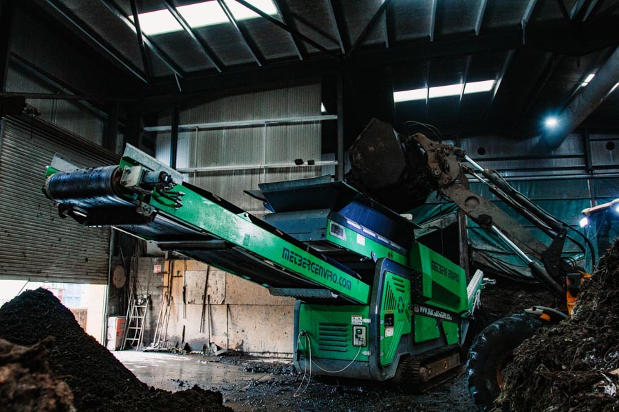 Digger loading waste onto conveyer belt